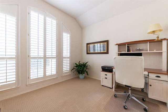 office space with baseboards, light carpet, and vaulted ceiling