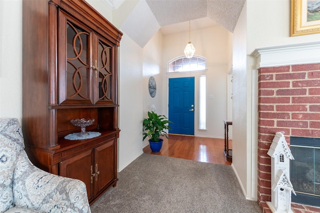 carpeted foyer entrance featuring a fireplace and lofted ceiling