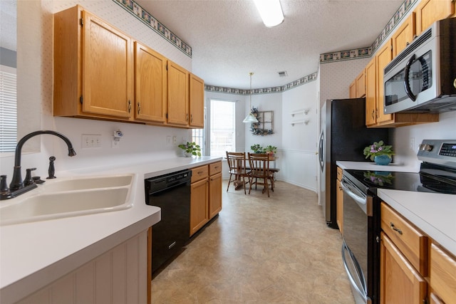 kitchen with light countertops, appliances with stainless steel finishes, hanging light fixtures, a textured ceiling, and a sink