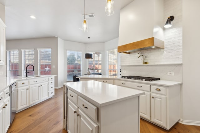 kitchen with gas cooktop, visible vents, a peninsula, stainless steel dishwasher, and wall chimney range hood