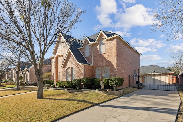 view of side of home featuring driveway, brick siding, a lawn, and a gate