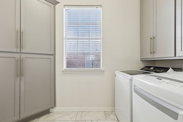 clothes washing area featuring baseboards, cabinet space, separate washer and dryer, and marble finish floor