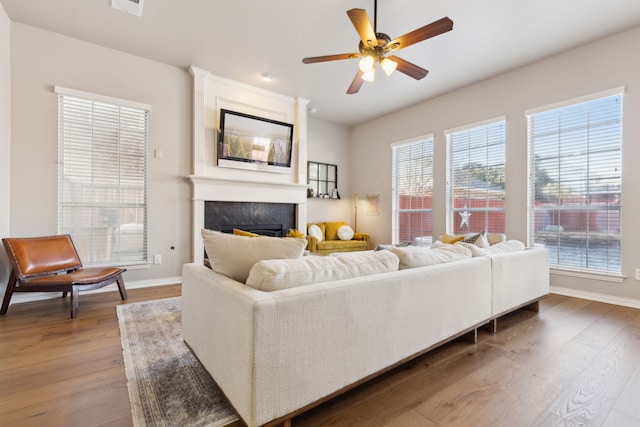 living area with a large fireplace, baseboards, and wood finished floors