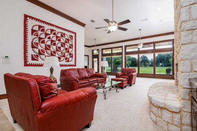 carpeted living room featuring visible vents, a stone fireplace, ornamental molding, and a ceiling fan