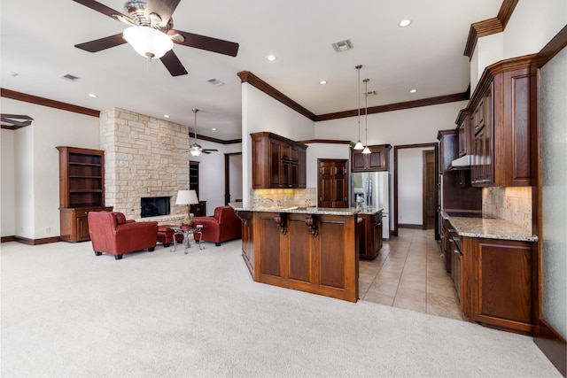 kitchen featuring open floor plan, a breakfast bar area, stainless steel refrigerator with ice dispenser, and light stone countertops