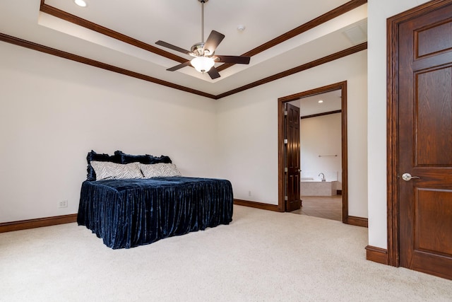 carpeted bedroom with crown molding, ensuite bathroom, baseboards, and a tray ceiling