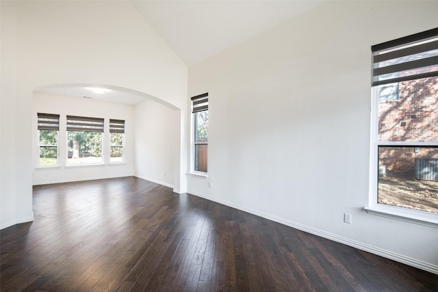 unfurnished room featuring baseboards, arched walkways, high vaulted ceiling, and dark wood-style flooring