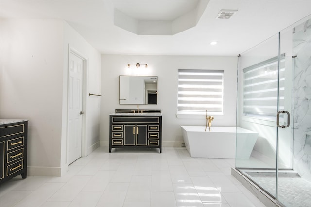 bathroom featuring vanity, visible vents, a stall shower, a freestanding bath, and a raised ceiling