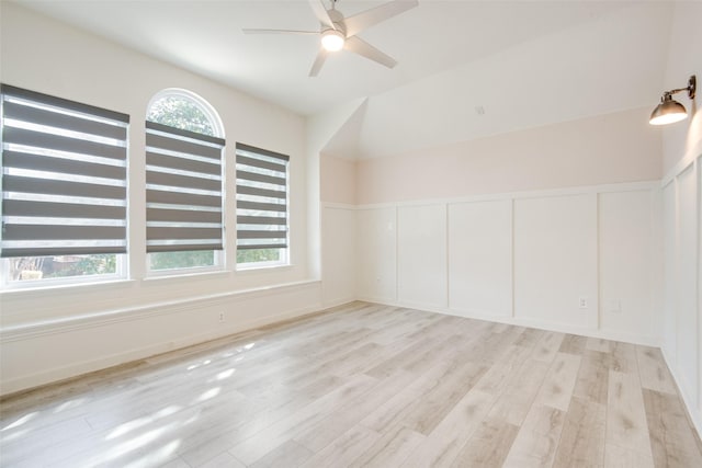 unfurnished room featuring ceiling fan, a wainscoted wall, light wood-style flooring, and a decorative wall