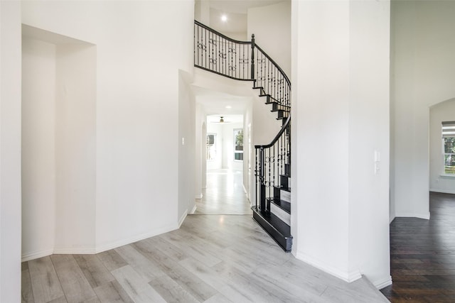 entryway with baseboards, stairs, a towering ceiling, and wood finished floors