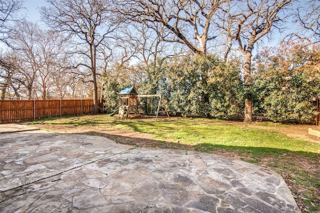 view of yard featuring a patio area, a playground, and fence