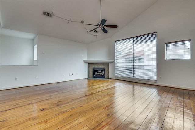 unfurnished living room featuring a ceiling fan, baseboards, visible vents, a tile fireplace, and hardwood / wood-style flooring