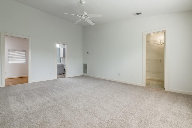 unfurnished bedroom with a walk in closet, carpet, and visible vents