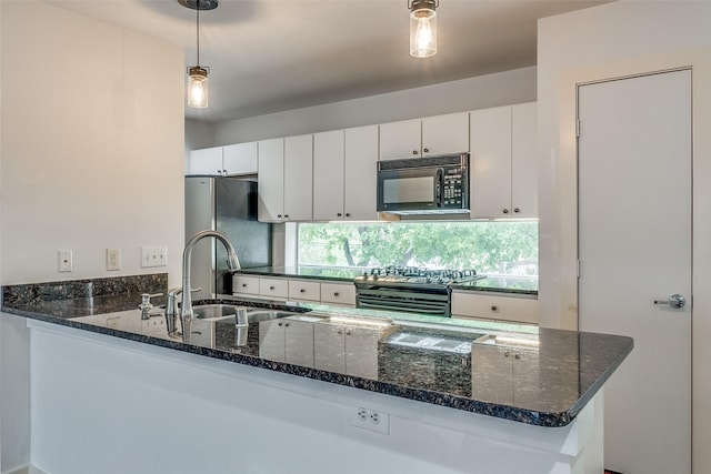 kitchen with pendant lighting, a sink, dark stone countertops, white cabinetry, and stainless steel appliances