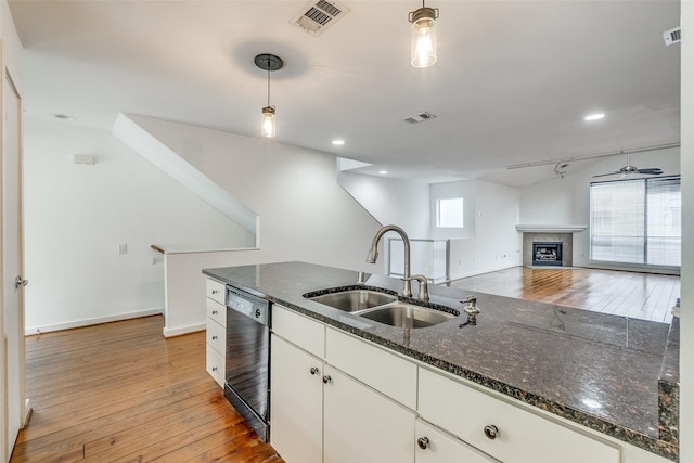 kitchen with visible vents, a sink, light wood finished floors, dishwashing machine, and hanging light fixtures