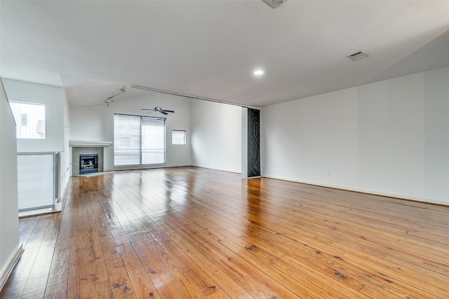 unfurnished living room with visible vents, a ceiling fan, wood-type flooring, a fireplace, and baseboards