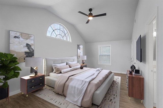 bedroom featuring a ceiling fan, light wood-type flooring, baseboards, and vaulted ceiling