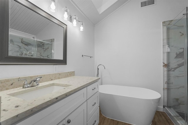 full bathroom featuring a marble finish shower, visible vents, a freestanding bath, vaulted ceiling, and wood finished floors