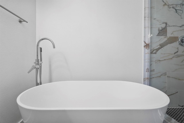 bathroom with a soaking tub and a tile shower