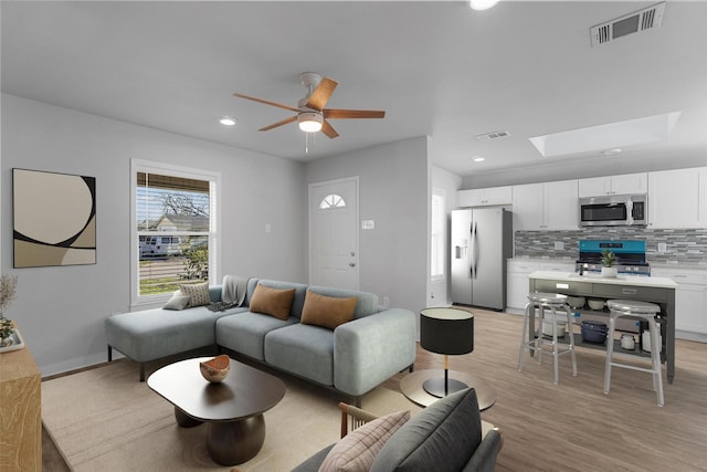 living area featuring recessed lighting, visible vents, a skylight, and light wood-style flooring