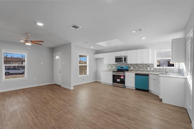 kitchen featuring visible vents, light wood-style floors, appliances with stainless steel finishes, and decorative backsplash