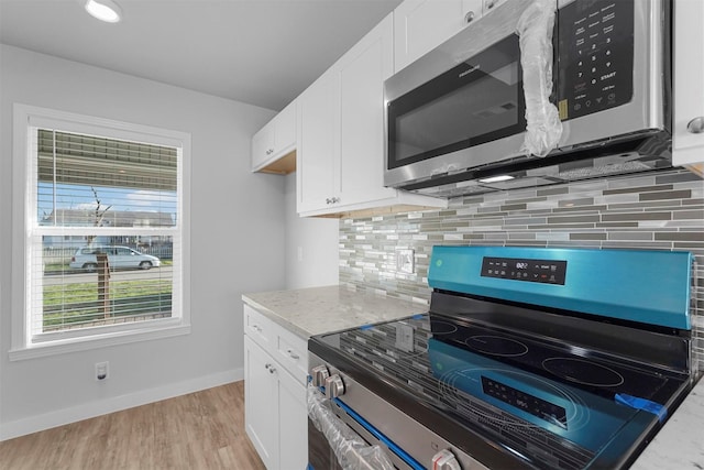 kitchen with white cabinetry, appliances with stainless steel finishes, light wood finished floors, decorative backsplash, and baseboards