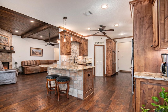 kitchen featuring brown cabinetry, visible vents, a peninsula, and a sink