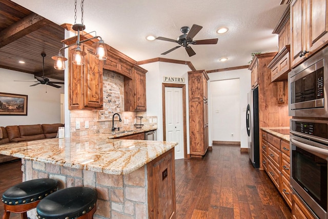 kitchen featuring backsplash, light stone countertops, dark wood finished floors, a peninsula, and stainless steel appliances