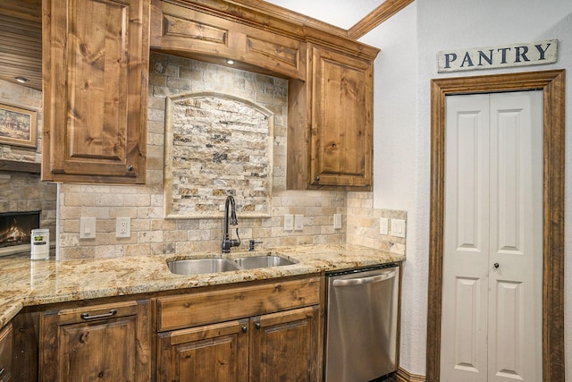 kitchen with light stone countertops, a fireplace, a sink, dishwasher, and backsplash