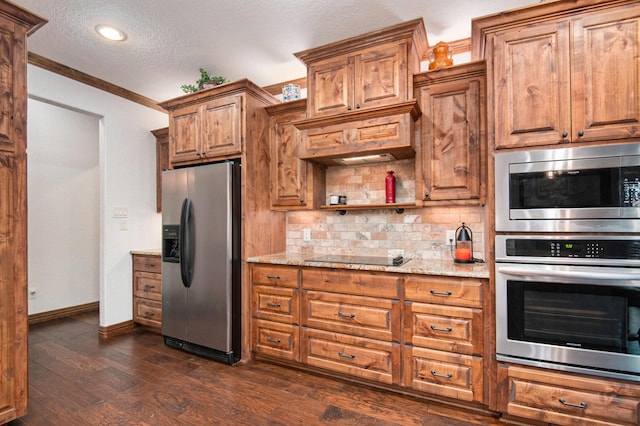 kitchen with tasteful backsplash, dark wood finished floors, light stone counters, appliances with stainless steel finishes, and brown cabinetry