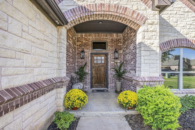 view of exterior entry featuring brick siding and stone siding