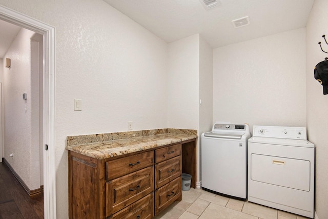 clothes washing area featuring light tile patterned flooring, laundry area, washing machine and dryer, and visible vents