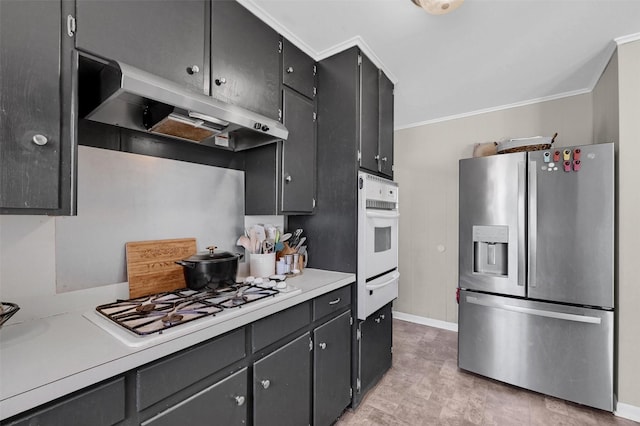 kitchen with under cabinet range hood, light countertops, ornamental molding, white appliances, and a warming drawer