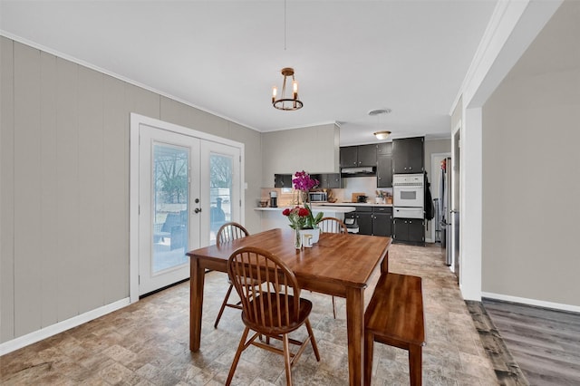 dining room featuring a notable chandelier, french doors, crown molding, and baseboards