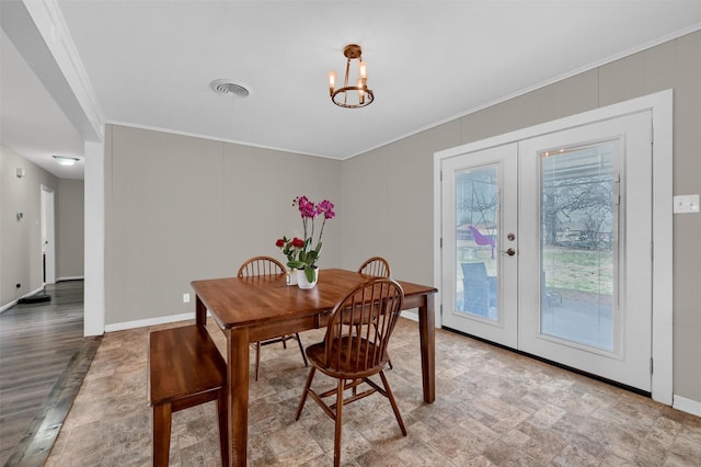 dining space featuring visible vents, baseboards, ornamental molding, french doors, and a notable chandelier