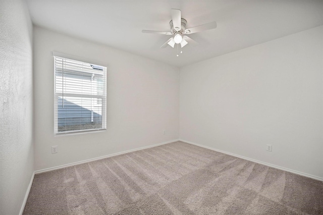 carpeted spare room with a ceiling fan and baseboards