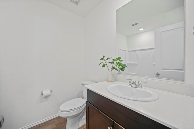 bathroom with visible vents, baseboards, toilet, wood finished floors, and vanity