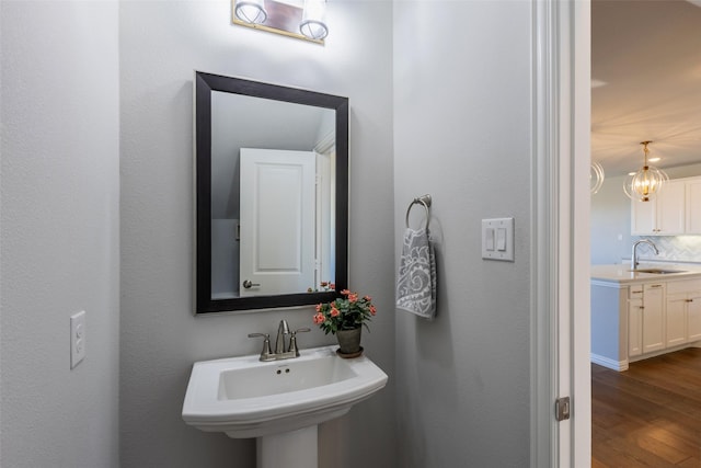 bathroom with decorative backsplash, wood finished floors, and a sink