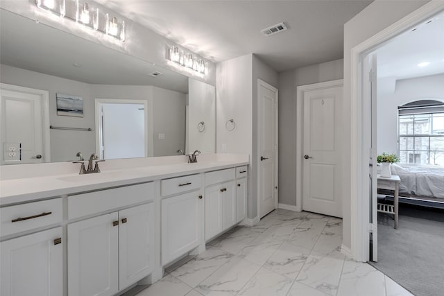 ensuite bathroom with visible vents, marble finish floor, a sink, connected bathroom, and double vanity