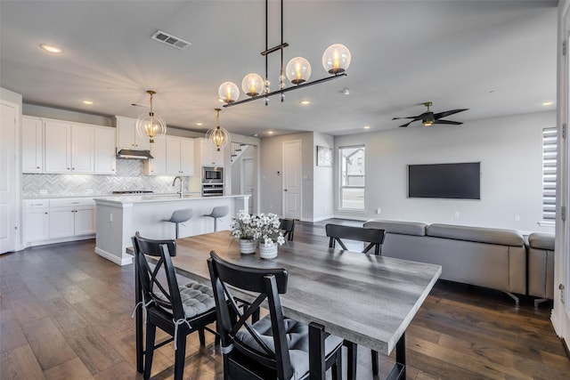 dining space with dark wood-style floors, visible vents, plenty of natural light, and a ceiling fan