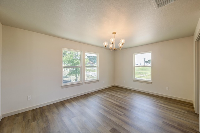 empty room featuring visible vents, plenty of natural light, and wood finished floors