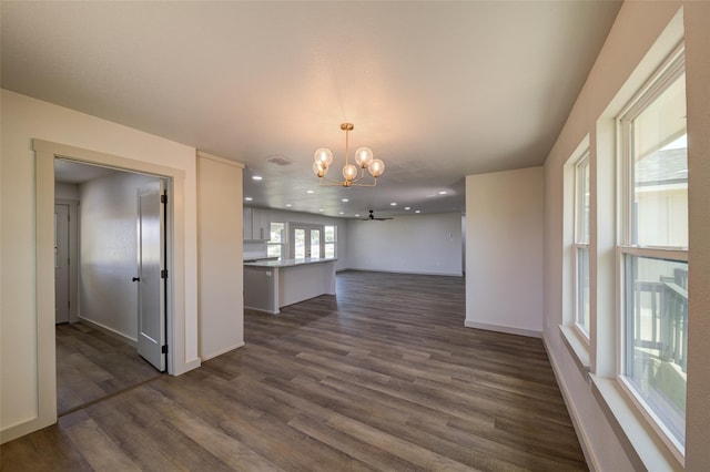 interior space with a notable chandelier, recessed lighting, dark wood-type flooring, and baseboards