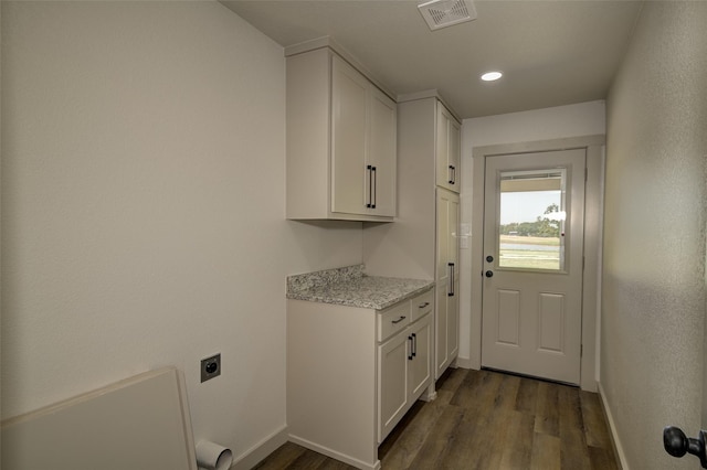 washroom featuring electric dryer hookup, visible vents, dark wood-type flooring, cabinet space, and baseboards