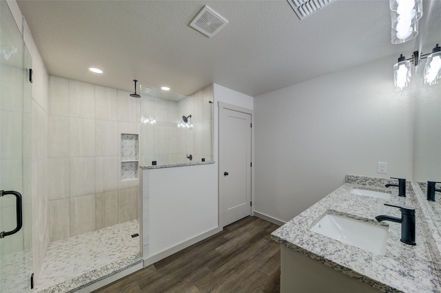 bathroom featuring a sink, visible vents, wood finished floors, and a shower stall