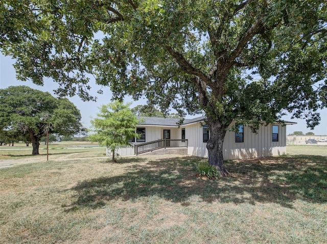 view of front facade with board and batten siding and a front lawn