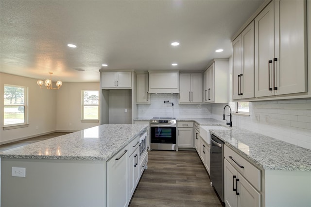 kitchen with dark wood-type flooring, a sink, backsplash, a center island, and stainless steel appliances