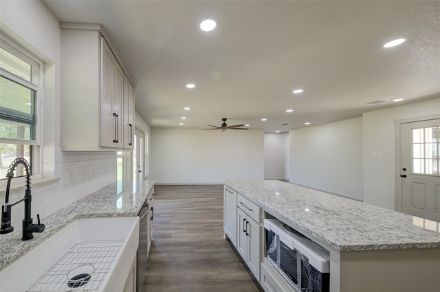 kitchen featuring tasteful backsplash, dark wood-type flooring, dishwasher, recessed lighting, and a sink