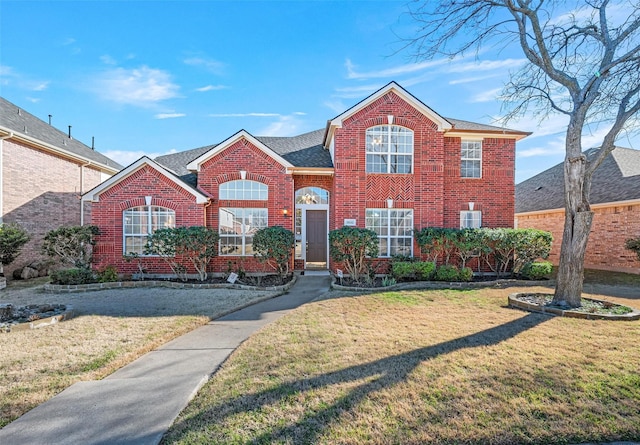 traditional-style home featuring brick siding, roof with shingles, and a front yard