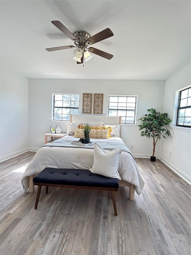 bedroom with ceiling fan, baseboards, and wood finished floors