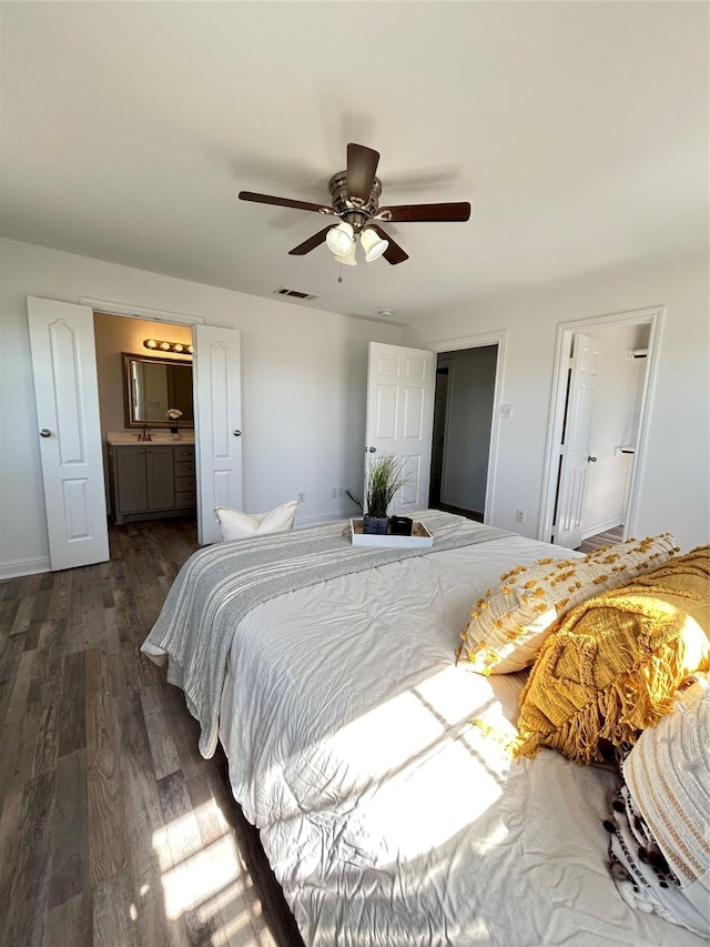 bedroom with visible vents, a ceiling fan, ensuite bath, dark wood finished floors, and baseboards